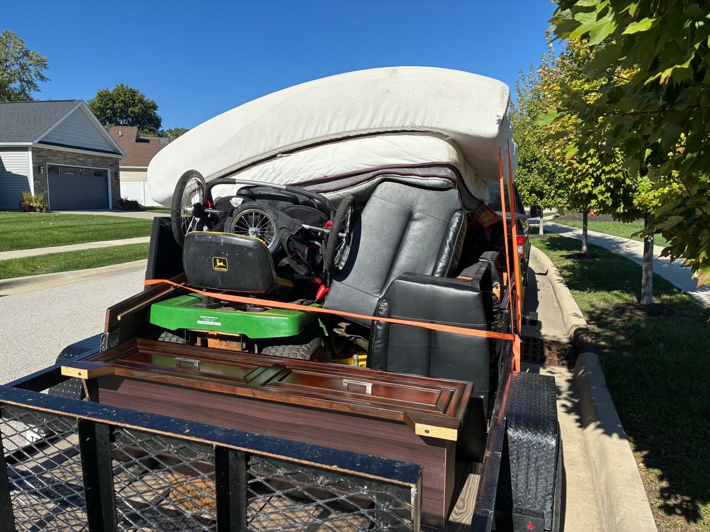 A recliner, riding mower and mattress strapped onto a FlexHaul trailer