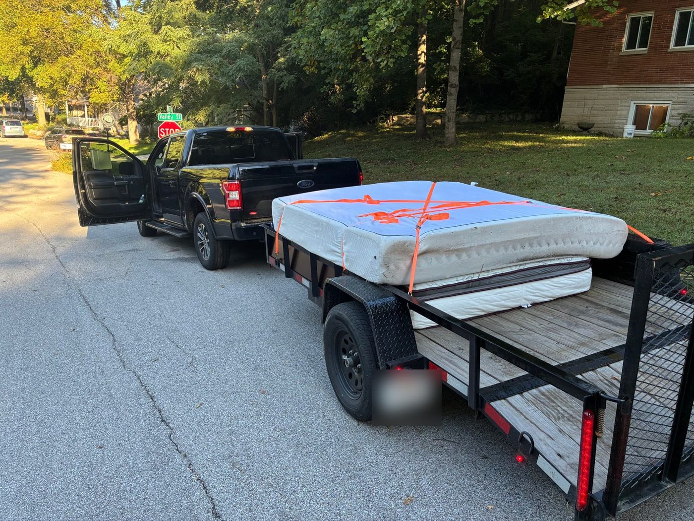 A FlexHaul pickup truck and trailer loaded with a mattress and dresser, ready to haul
