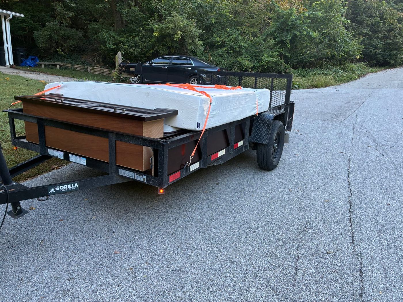 A FlexHaul trailer loaded with a mattress and dresser, strapped down